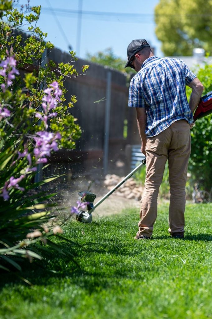 a man using a lawn trimmer to cut grass
